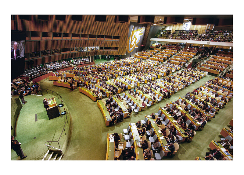 Wide-angle view of a large assembly hall filled with hundreds of seated delegates in a tiered auditorium.
