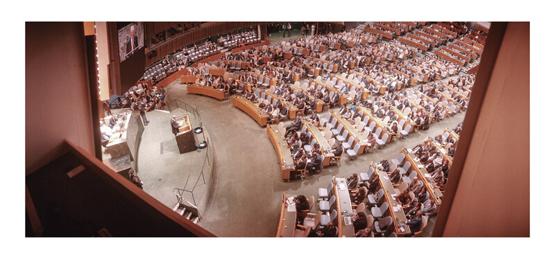 Aerial view of a large auditorium filled with seated attendees and a central stage platform.