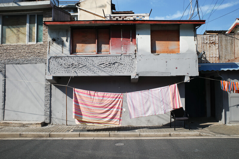 Weathered residential building with laundry hanging on clothesline in front.