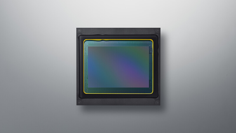 Camera image sensor with green and gold frame against dark background.