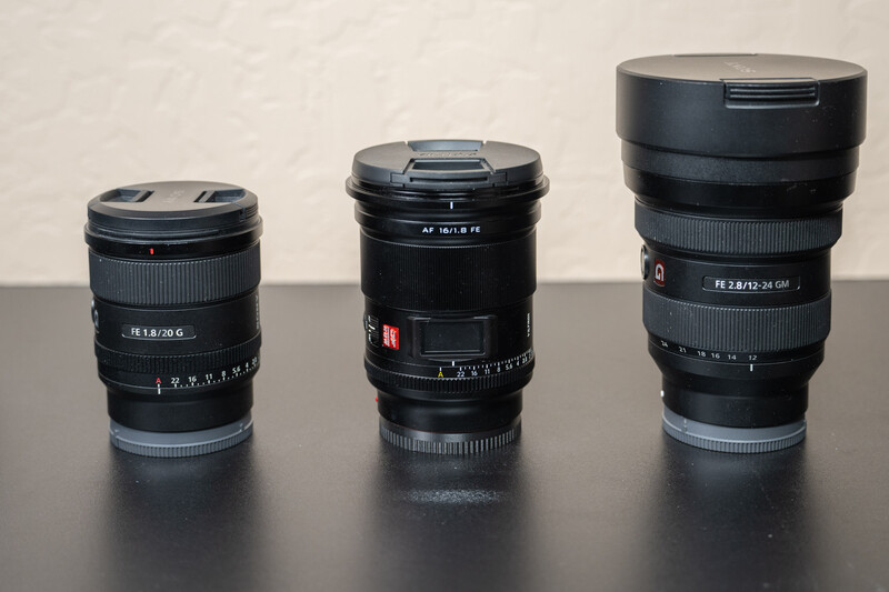 Three black camera lenses of increasing size arranged side by side on a dark surface.
