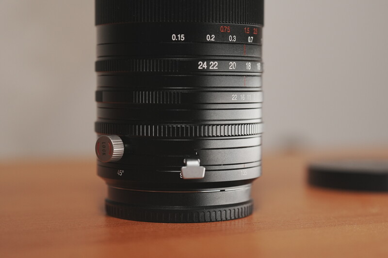 Close-up of a manual focus lens showing aperture and focal length scales on its barrel.