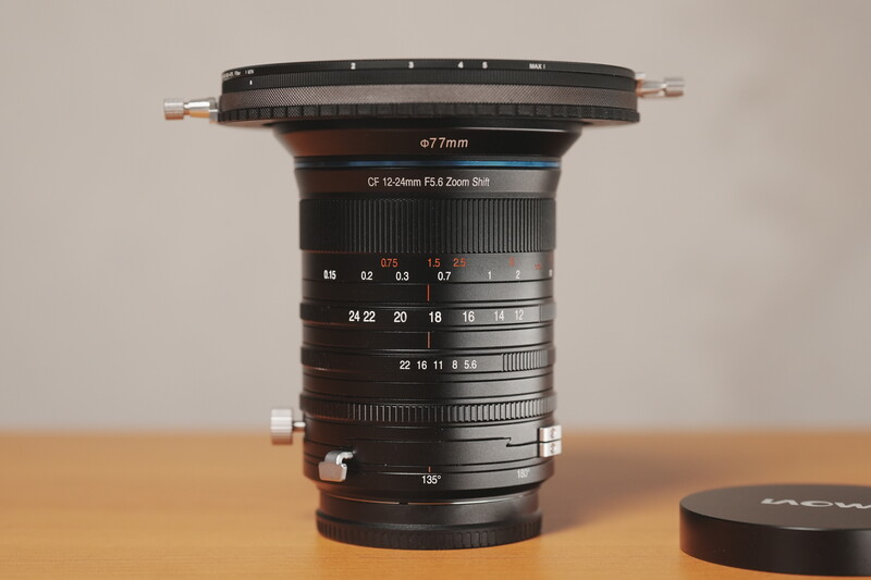 Wide-angle lens mounted on wooden surface showing aperture and focal length markings.
