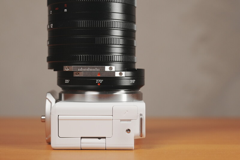 Vintage telephoto lens mounted on a white camera body against a wooden surface.