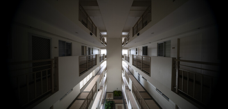 Symmetrical upward view of a narrow residential courtyard with white-walled buildings and metal railings.