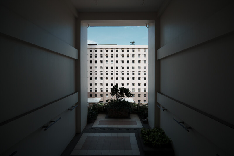 View through a narrow concrete hallway framing a modernist apartment building facade.