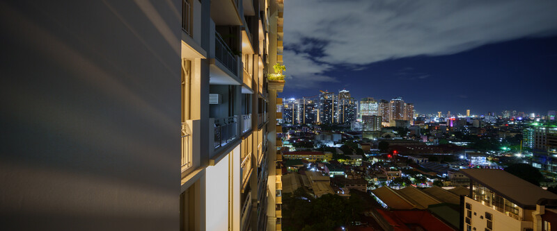 Modern apartment building in foreground with illuminated city skyline at dusk in the background.