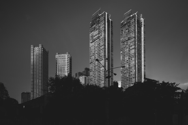 Silhouetted high-rise residential towers rising against a gray sky in this black and white cityscape.