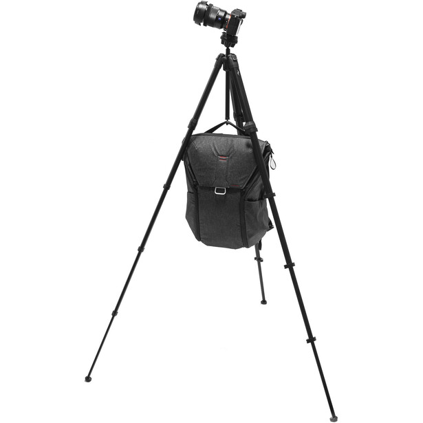 Camera mounted on tripod with black camera bag hanging from the center column.