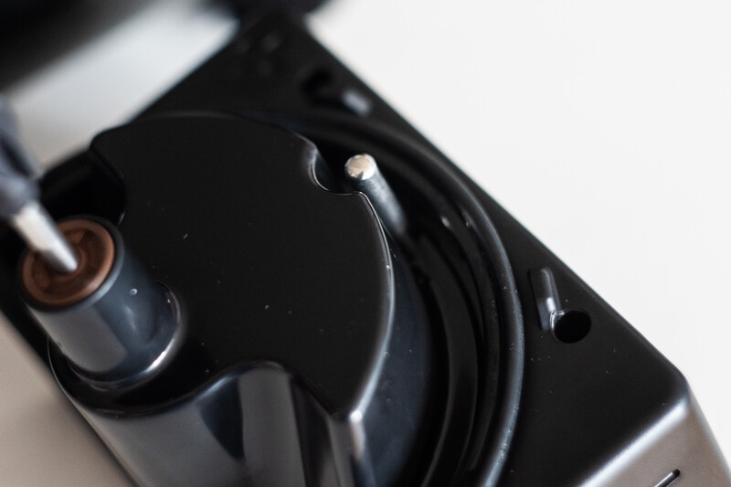 Close-up of an in-ear monitor with coiled black cable on light background.