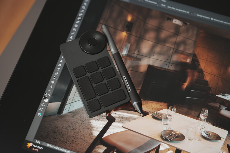MIDI controller positioned on desk with photography editing software displayed on monitor behind it.
