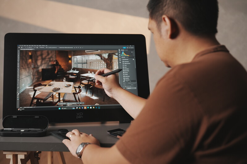 Photographer editing a portrait image in post-processing software on a laptop display.