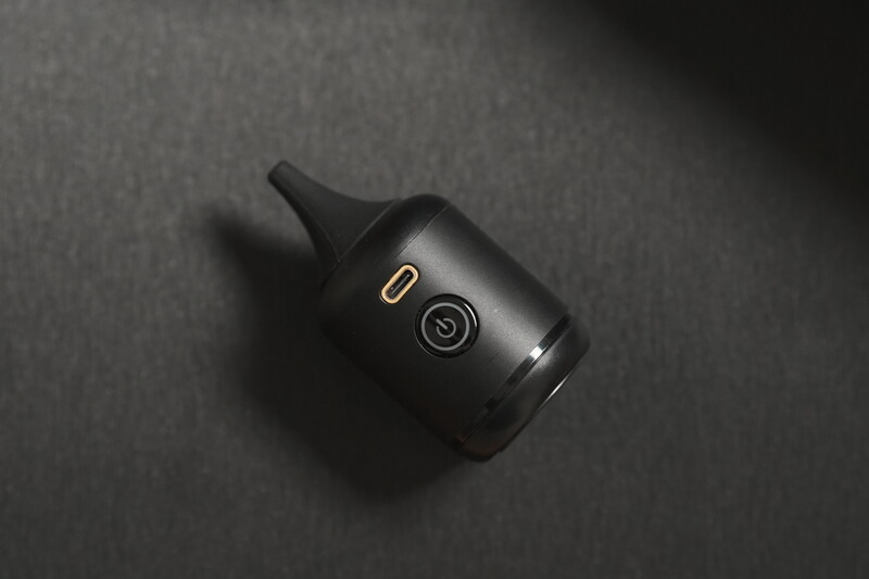 Black compact device with USB port and power button on textured gray surface.