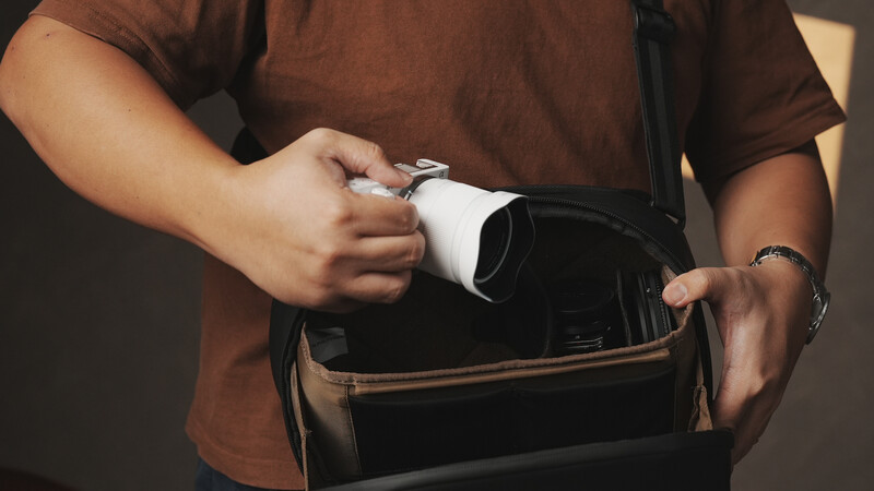 Person in brown shirt opening empty black wallet, revealing no contents inside.