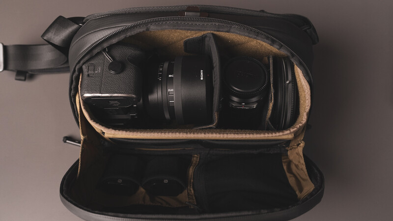 Camera bag interior with organized compartments holding a camera body and lens.
