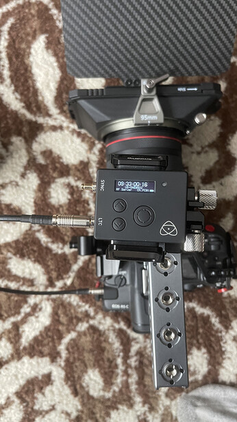 Professional cinema camera mounted on a tripod head, viewed from above on a patterned rug.