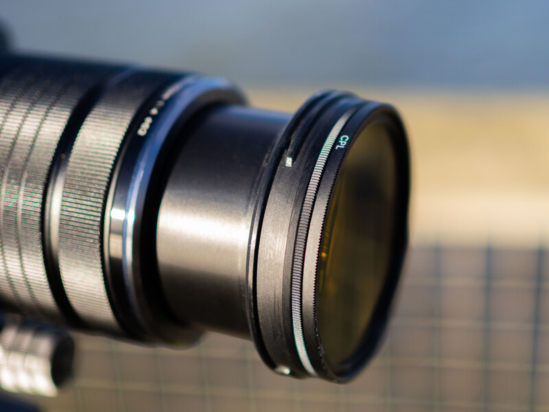 Close-up of telephoto lens elements and filter rings with shallow depth of field.
