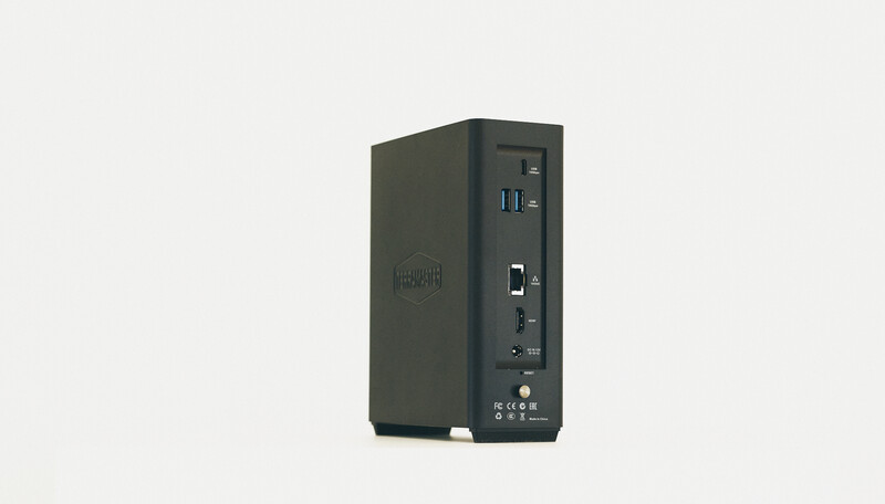 Compact desktop computer tower with dark gray casing, front-facing ports, and minimal branding visible.