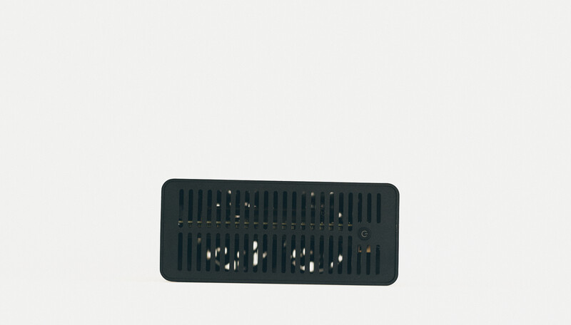 Dark rectangular device with vertical ribbed cooling fins and circular ventilation ports on a light gray background.