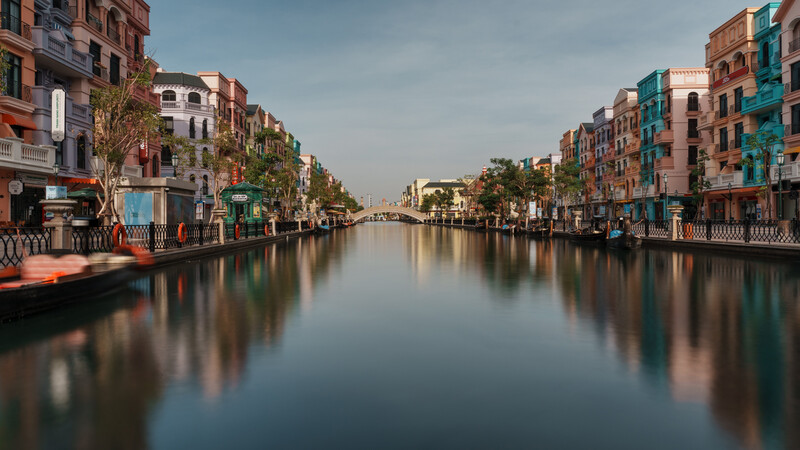 Colorful residential buildings lining a calm canal with perfect mirror reflections in still water.