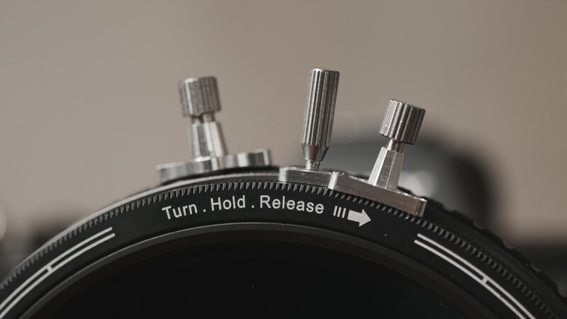 Close-up of a mechanical timer's top with three metal adjustment knobs and instruction text reading 'Turn. Hold. Release.'