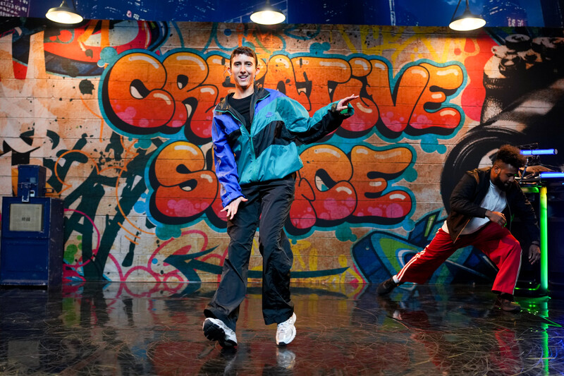 Breakdancer in front of a graffiti covered wall.