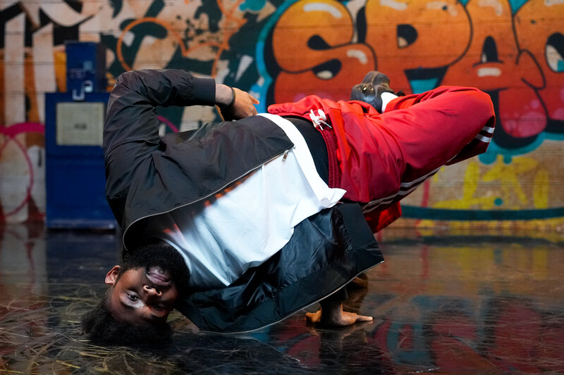 Breakdancer in front of a graffiti covered wall.