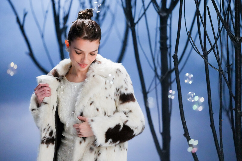 Model wearing fur coat on an artificial winter set.