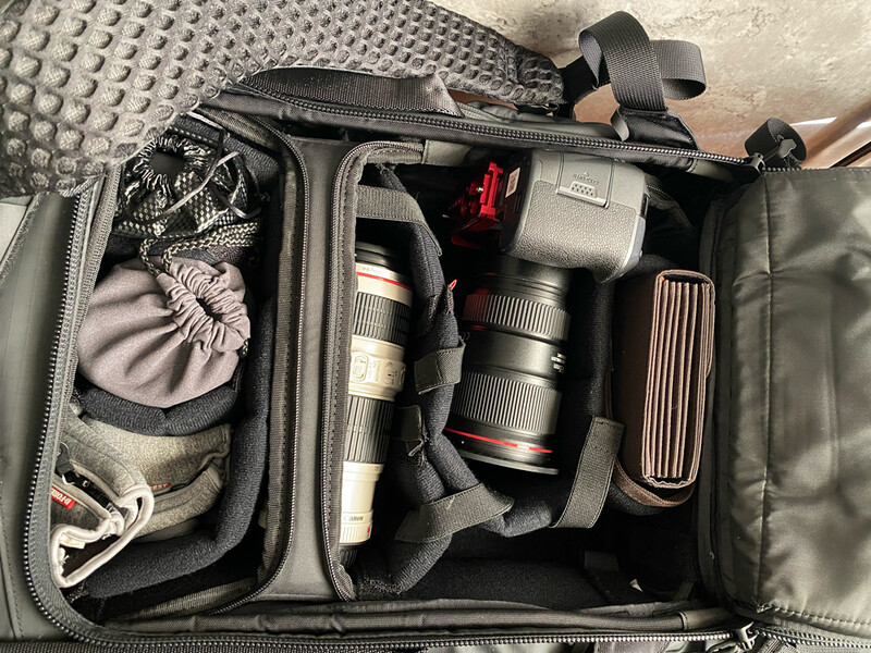 Camera gear organized inside a black padded camera bag with compartments and foam inserts.
