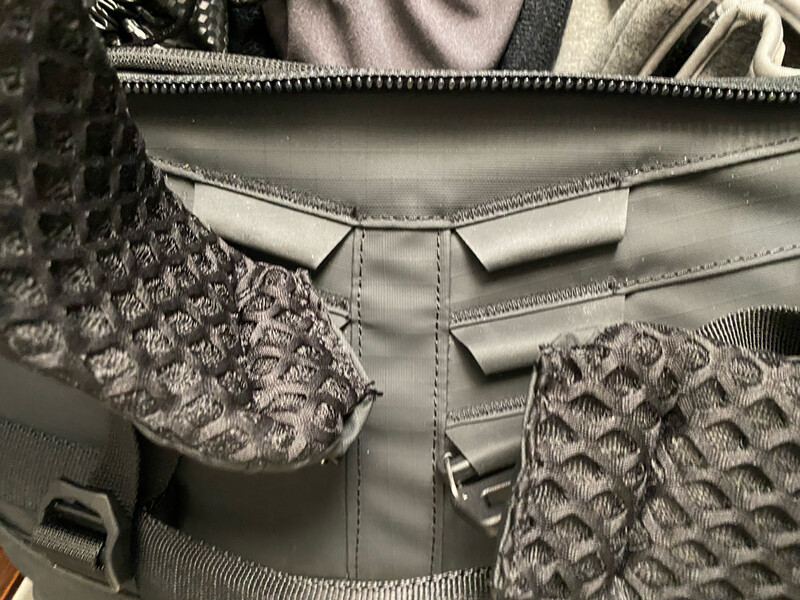 Interior detail of a padded backpack or bag showing quilted fabric pockets and gray nylon construction.
