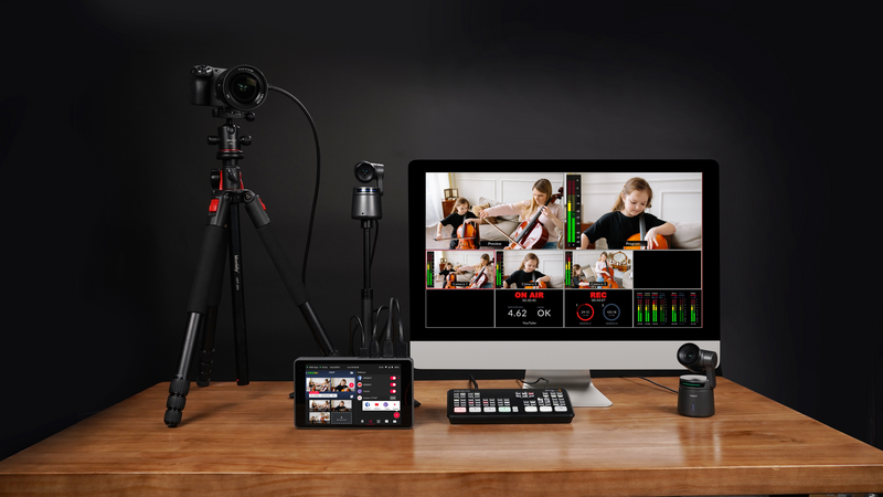 Professional live streaming and video production setup on wooden desk with camera, monitor, and control panels.
