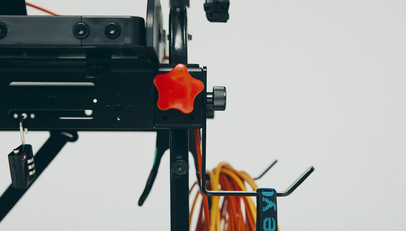 Close-up of a 3D printer with a red star-shaped knob and filament spool mounted on the side.