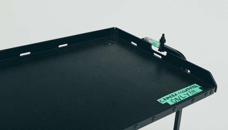 Black modular tray system with textured surface and green labeling detail against neutral background.