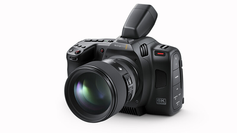 Black 6K cinema camera with attached prime lens and pop-up flash against white background.
