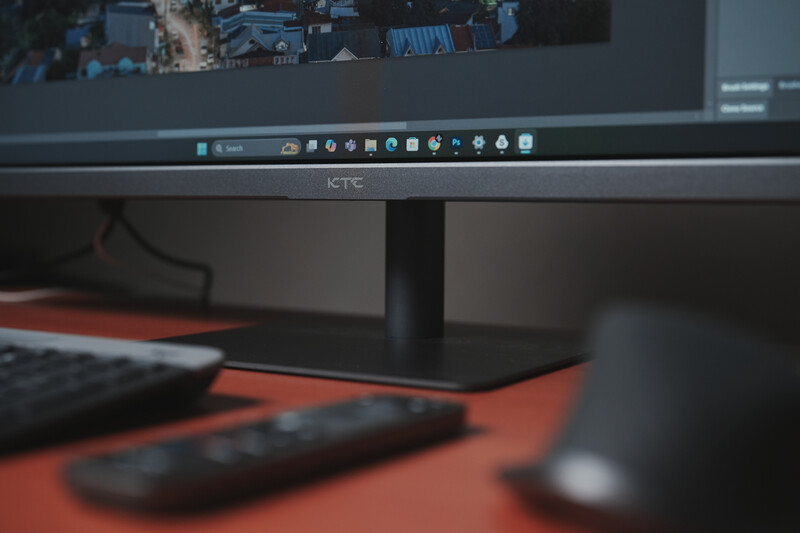 Desktop workspace with HTC monitor displaying photo editing software, keyboard, and mouse on orange desk surface.