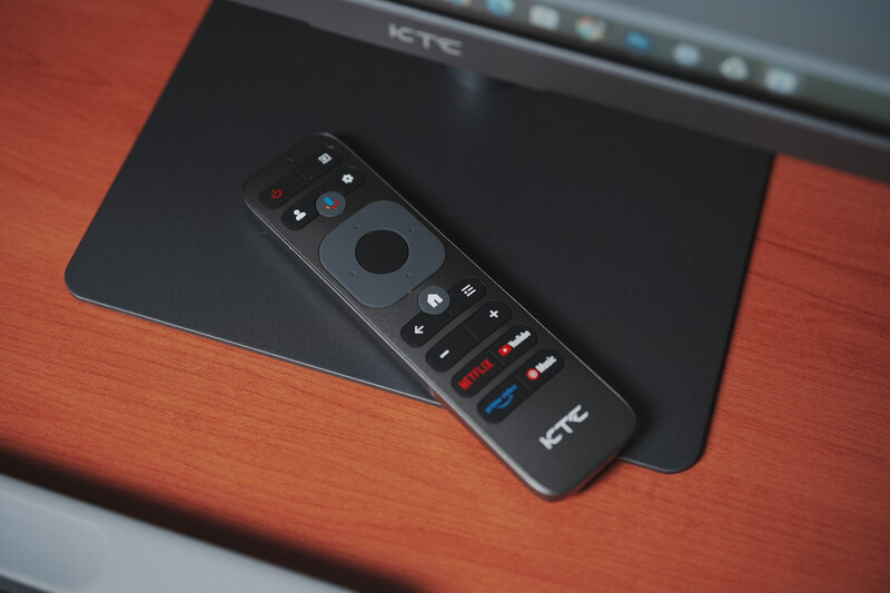 HTC media remote control resting on a tablet device against a wooden surface.