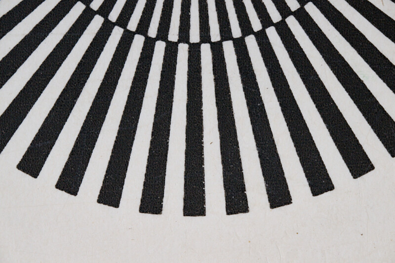 Black and white graphic pattern of radiating lines forming a semicircular fan or sunburst design.