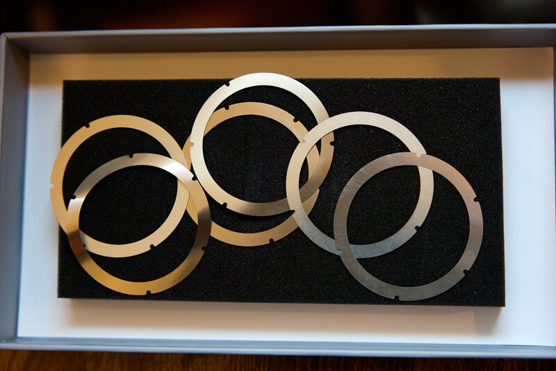 Metallic circular rings arranged in an overlapping pattern against a black background.