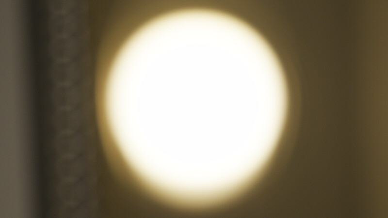 Bright circular light source with warm golden glow against neutral brown background.