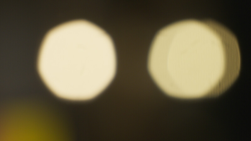 Two out-of-focus circular light sources against a dark background, demonstrating bokeh rendering.