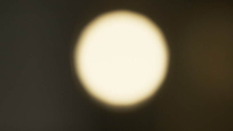 Bright circular light source with soft golden halo against dark background.