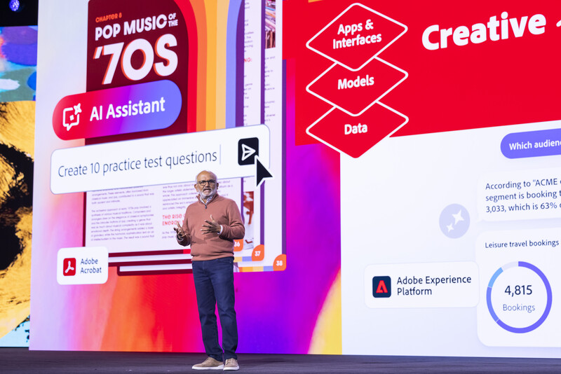 Speaker presenting on stage with colorful gradient background and digital interface displaying creative industry content.