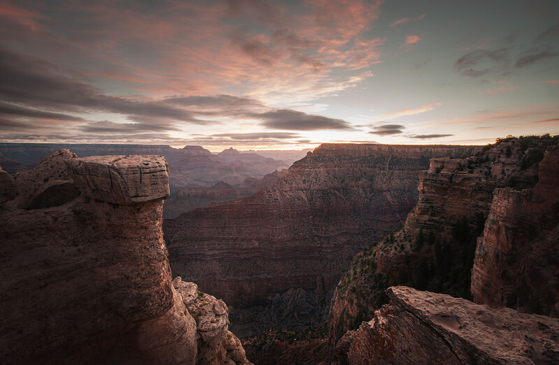 Rocky canyon vista at sunset with layered stone formations and dramatic sky.