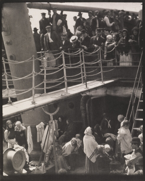 Crowded ship deck with passengers at railings during what appears to be embarkation or disembarkation.