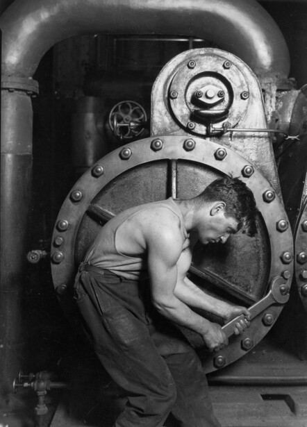 Worker in industrial boiler or furnace chamber, black and white photograph.