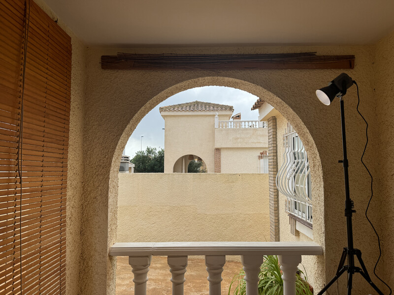 Arched doorway framing a Mediterranean villa exterior with balustrade railing in foreground.