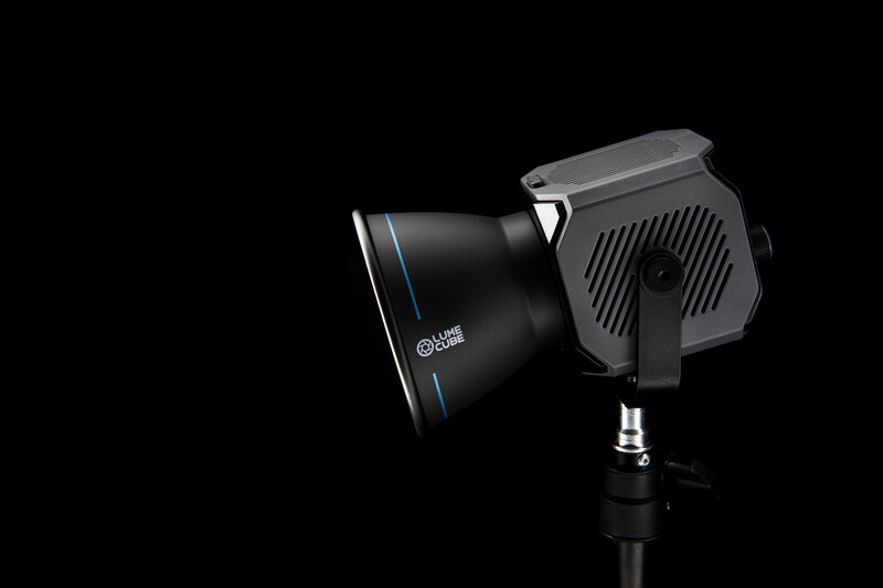 Professional LED spotlight with reflector and power supply unit against black background.