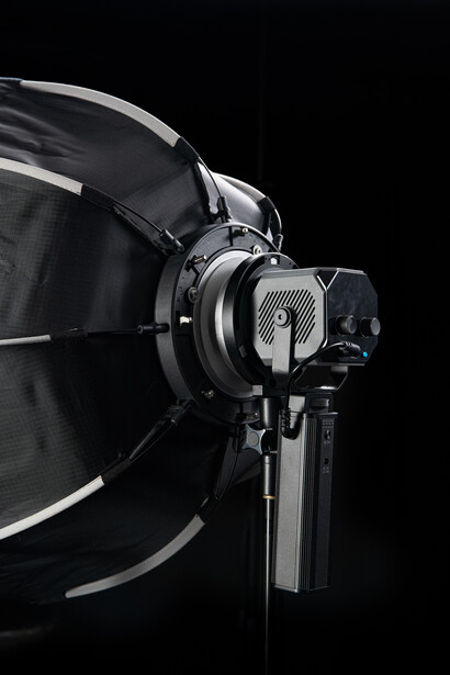 Professional studio light with large softbox and mounting bracket against black background.