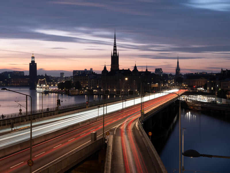 Long exposure photograph of city traffic on a bridge at dusk with light trails streaking across the frame.