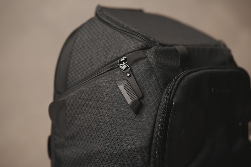 Close-up of a black backpack with textured fabric and dual zippered compartments with metal hardware.